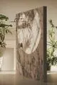 Wandhalterung für Dusche mit schlankem Design, montiert an einer marmorierten Wand, umgeben von Pflanzen. Ideal Standard ist in der Konstruktion erkennbar.